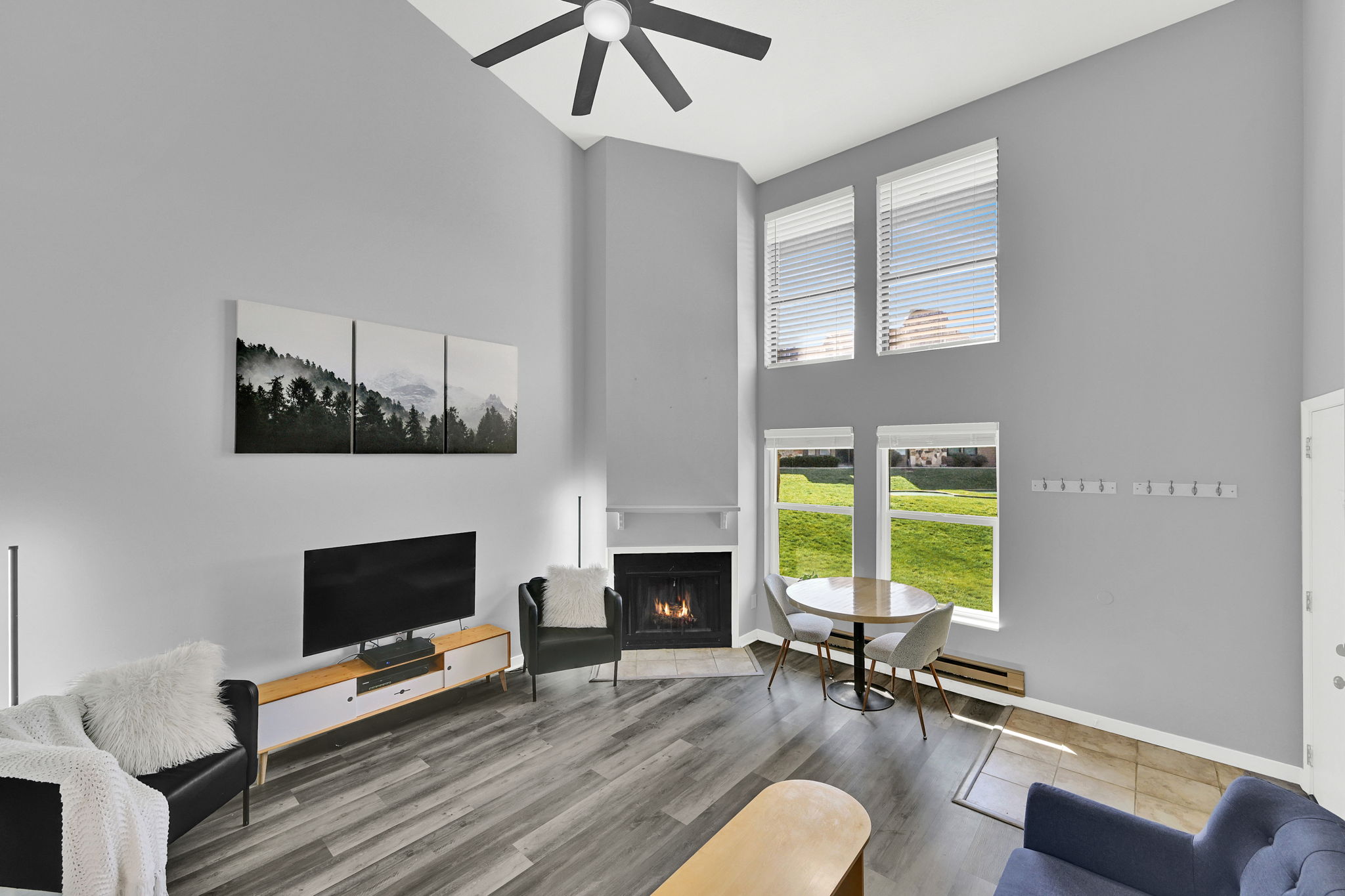 Lofted living room with upgraded, neutral LVP flooring, wood burning fireplace and modern finishes. New windows let in natural light.