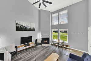 Lofted living room with upgraded, neutral LVP flooring, wood burning fireplace and modern finishes. New windows let in natural light.