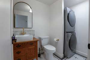Bathroom with vanity, stacked washer and dryer, and tile patterned flooring