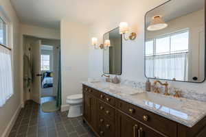 Ensuite bathroom featuring double vanity and dark tile patterned flooring