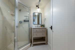 Full bathroom featuring vanity, a marble finish shower, and light tile patterned flooring