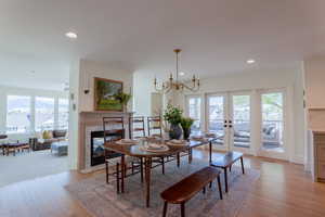 Dining space with hanging lights, light wood-type flooring, a fireplace, and french doors