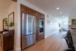 Kitchen featuring stainless steel appliances, light wood-style flooring, a fireplace, and recessed lighting