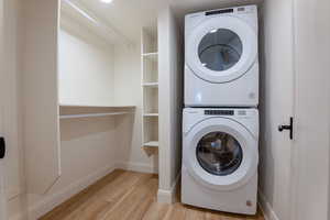 Laundry area featuring stacked washer and dryer and light wood finished floors
