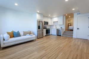 Kitchen with light countertops, white cabinetry, stainless steel appliances, light wood-style flooring, and decorative backsplash