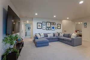 Living area with light carpet and recessed lighting