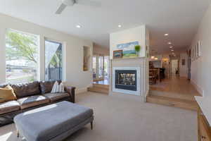 Living area with light colored carpet, recessed lighting, a fireplace, and a ceiling fan
