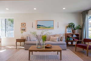 Living room with plenty of natural light, light wood finished floors, and recessed lighting