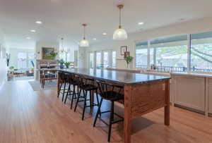 Kitchen featuring decorative light fixtures, dark stone countertops, light wood-style floors, and a breakfast bar