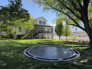 Rear view of property with a trampoline, a patio, and a balcony
