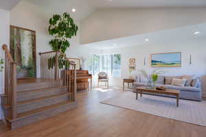 Living room with light wood finished floors, lofted ceiling, and recessed lighting