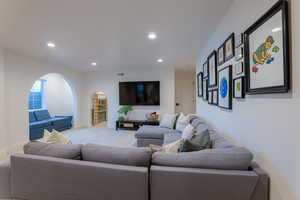 Living area featuring recessed lighting, arched walkways, and carpet floors