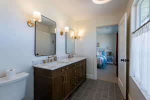 Full bathroom with ensuite bath, double vanity, and dark carpet