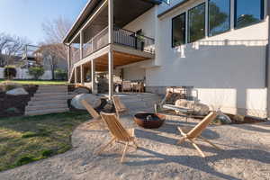 Back of property featuring a patio area, stucco siding, a fire pit, and a balcony