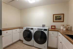 Laundry area featuring cabinet space, separate washer and dryer, and light tile patterned flooring