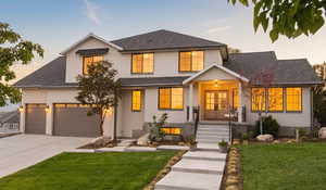 Modern inspired farmhouse featuring a shingled roof, a lawn, covered porch, driveway, and stucco siding