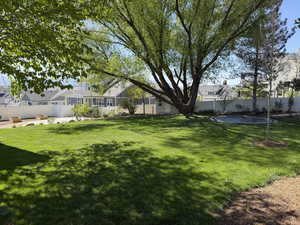 Fenced backyard featuring a residential view and a trampoline