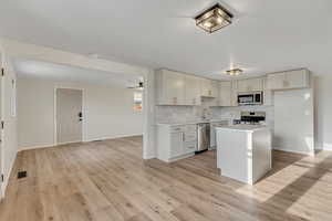 Kitchen with light countertops, stainless steel appliances, ceiling fan, a center island, and tasteful backsplash