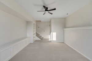 Empty room featuring ceiling fan, a decorative wall, and carpet floors