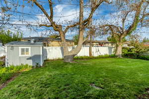 Fenced backyard featuring a storage unit