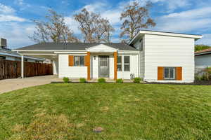 View of front of house with a carport, driveway, and a shingled roof