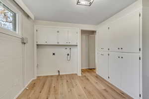 Laundry room featuring cabinet space, light wood finished floors, and hookup for an electric dryer