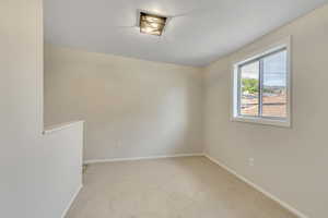 Spare room with light carpet and baseboards