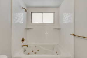 Full bathroom featuring a combined bath / shower with jetted tub and toilet