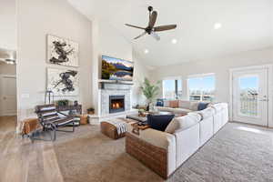 Living area featuring a ceiling fan, vaulted ceiling, a tiled fireplace, light wood-style floors, and recessed lighting