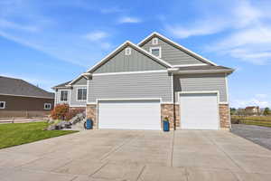 Craftsman-style home with board and batten siding, stone siding, concrete driveway, an attached garage, and a garage