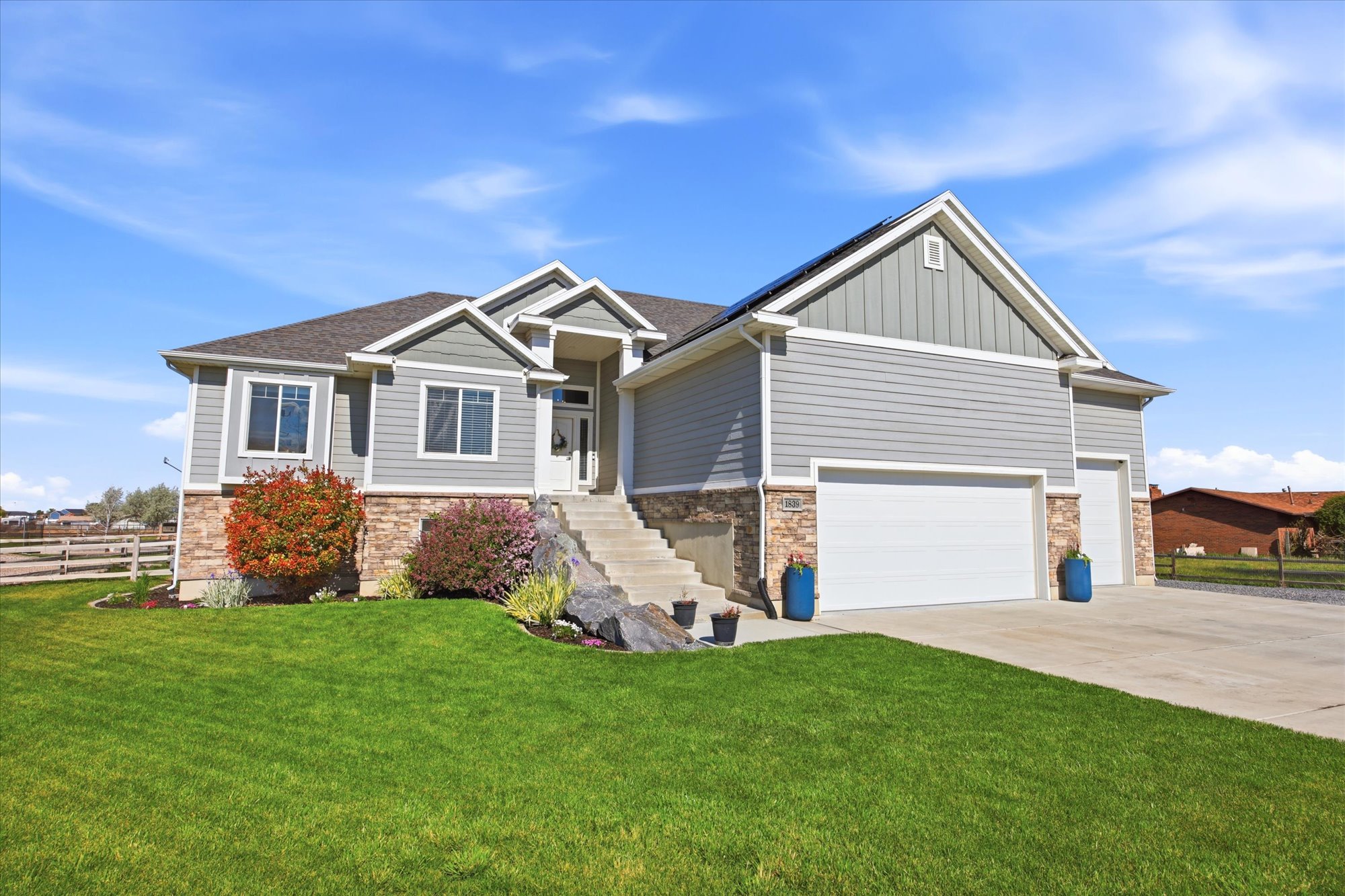 Craftsman-style house with stone siding, board and batten siding, driveway, and roof with shingles