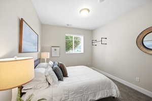 Bedroom featuring dark colored carpet and baseboards