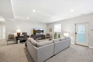 Living area with light carpet and recessed lighting