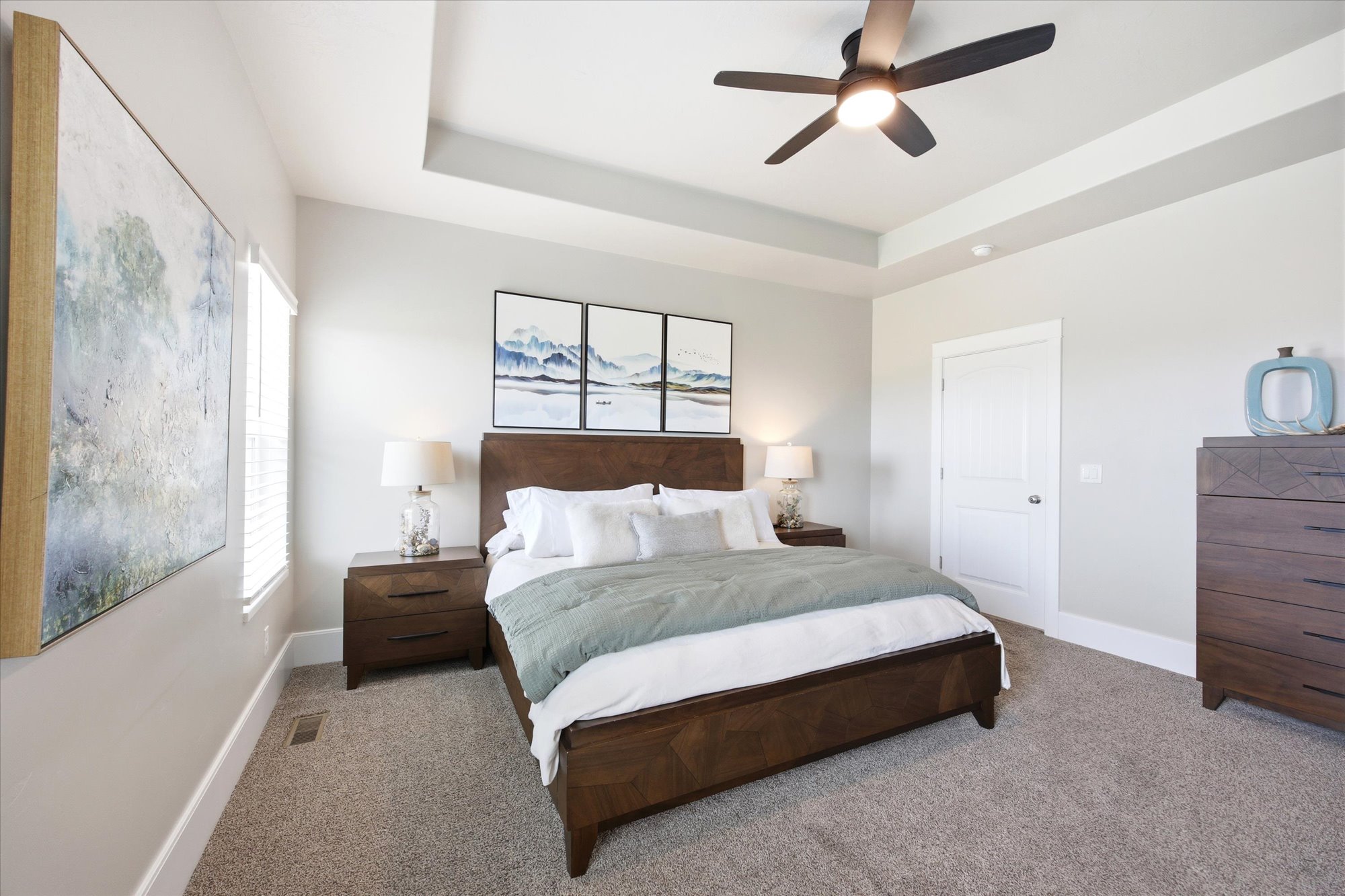 Bedroom with a tray ceiling, carpet, and a ceiling fan