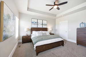 Bedroom with a tray ceiling, carpet, and a ceiling fan