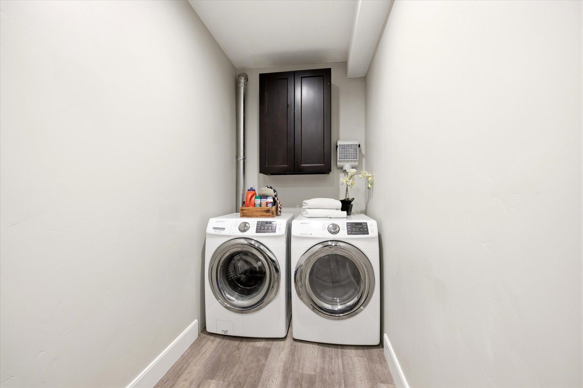 Laundry room with washer and dryer, light wood-style floors, and cabinet space