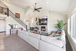 Living area with a warm lit fireplace, ceiling fan, vaulted ceiling, wood finished floors, and hanging lights