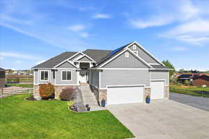Craftsman inspired home featuring board and batten siding, driveway, stone siding, and roof mounted solar panels
