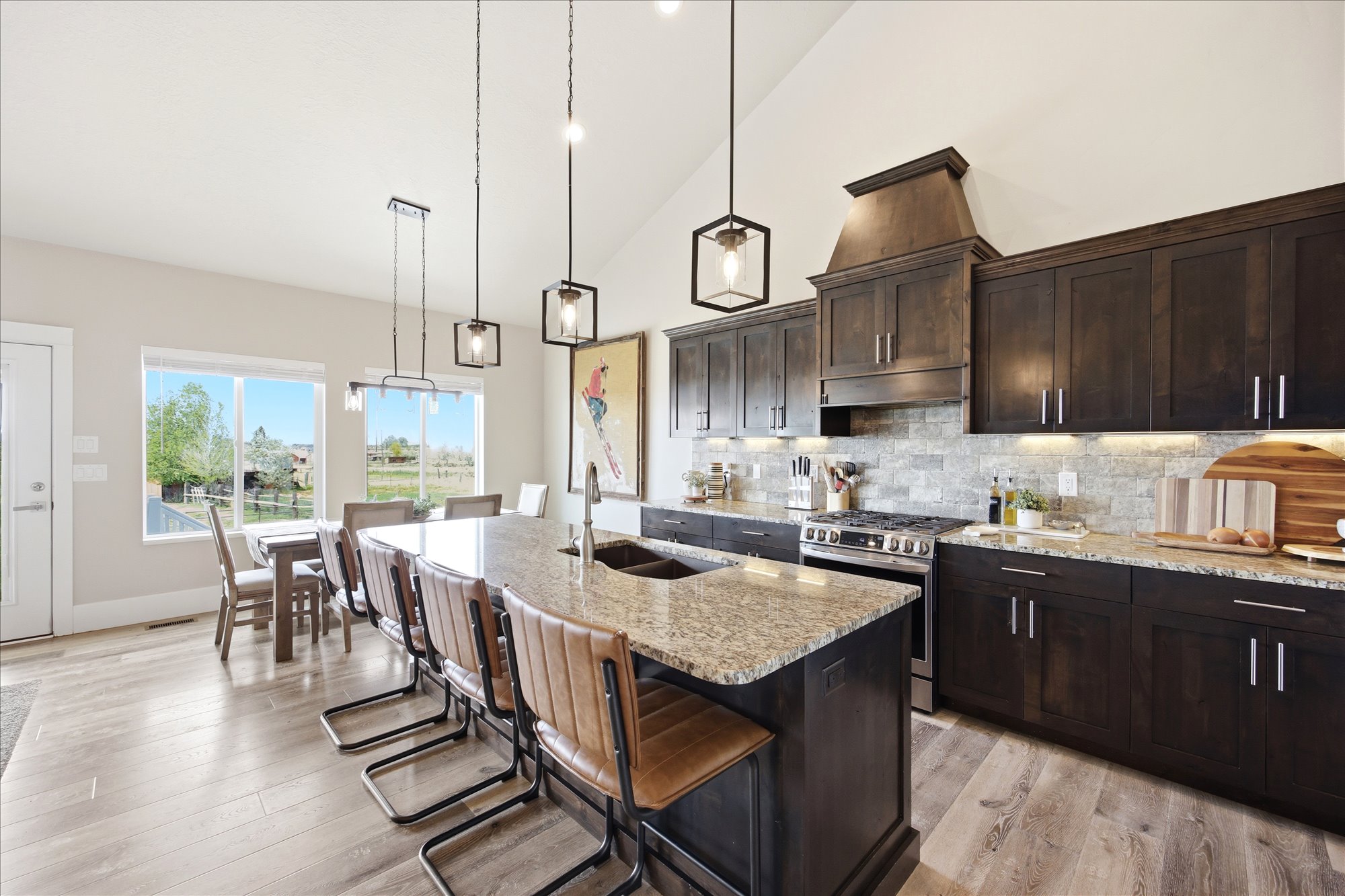 Kitchen featuring vaulted ceiling, light stone countertops, stainless steel gas range, a breakfast bar area, and light wood-style flooring