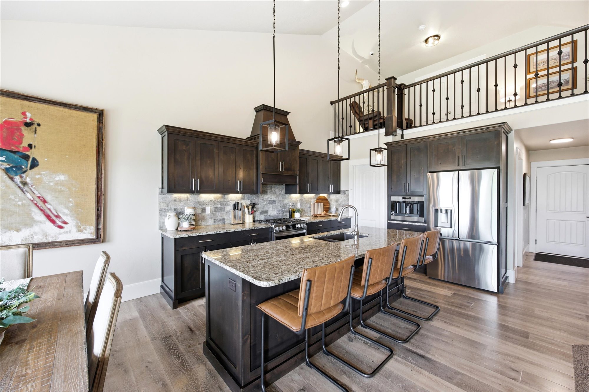 Kitchen featuring stainless steel appliances, light stone counters, a kitchen breakfast bar, dark wood finish cabinetry, and an island with sink