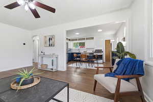 Living area featuring ceiling fan, arched walkways, and wood-type flooring