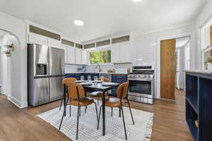 Dual tone kitchen featuring stainless steel appliances, light countertops, light wood-style floors, decorative backsplash, and dual tone cabinets