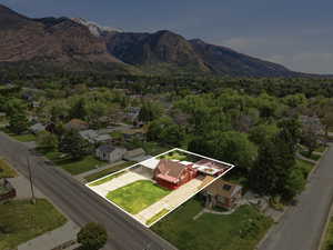 Aerial view of residential area with property boundaries highlighted and a mountain backdrop
