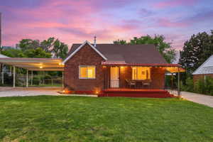 View of front facade with a porch, an attached carport, a yard, and brick siding