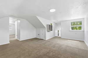 Additional living space with carpet flooring and a textured ceiling