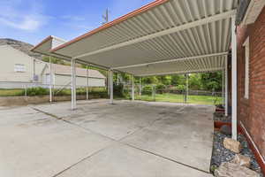 View of parking featuring a carport and a gate