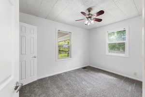 Carpeted empty room featuring ceiling fan and baseboards