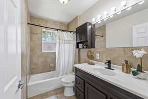 Full bathroom with vanity, shower / tub combo, tile walls, and tasteful backsplash