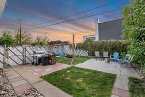 Yard at dusk with a patio, a gate, and a fenced backyard