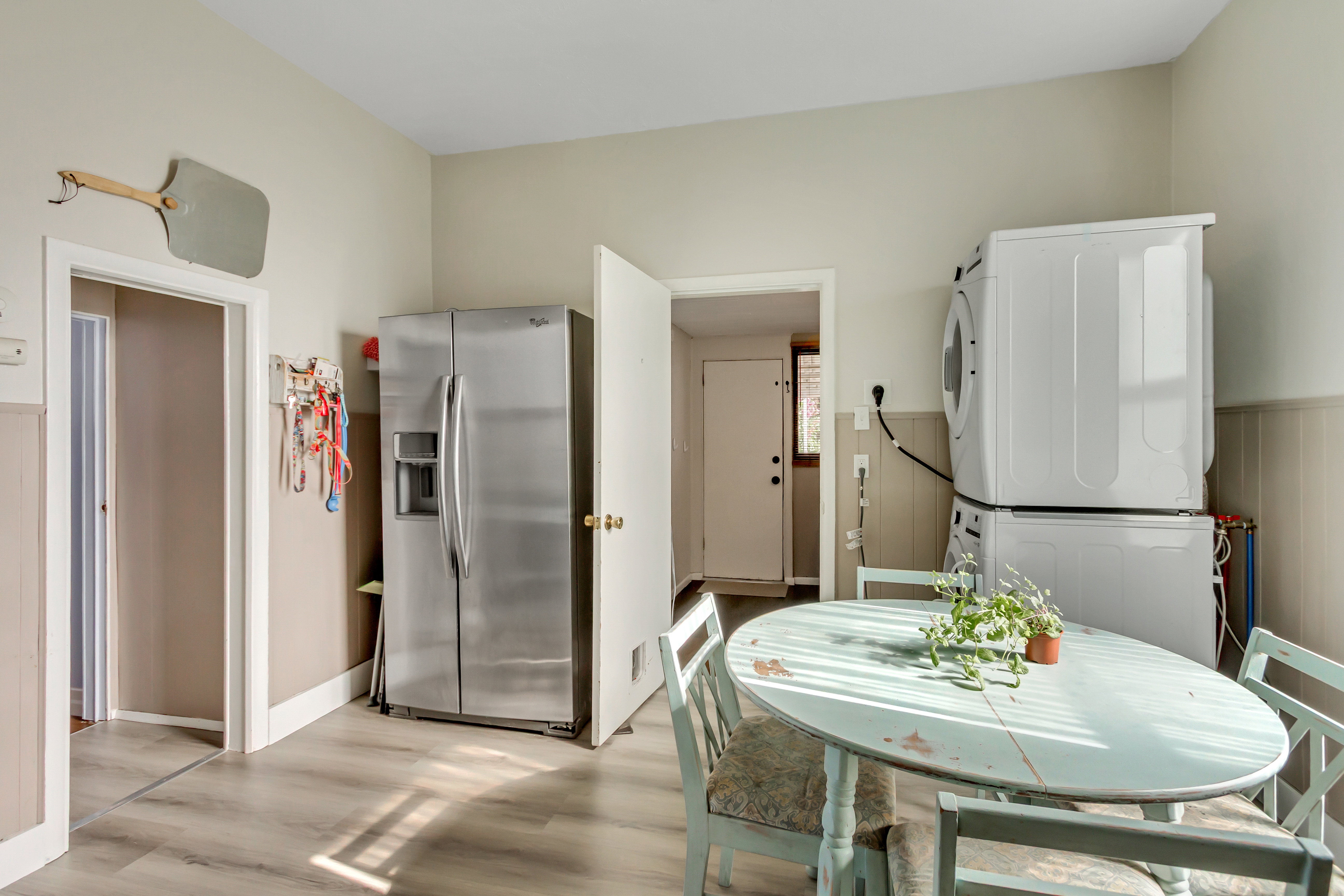 Dining room with light wood finished floors, wainscoting, and stacked washer and clothes dryer